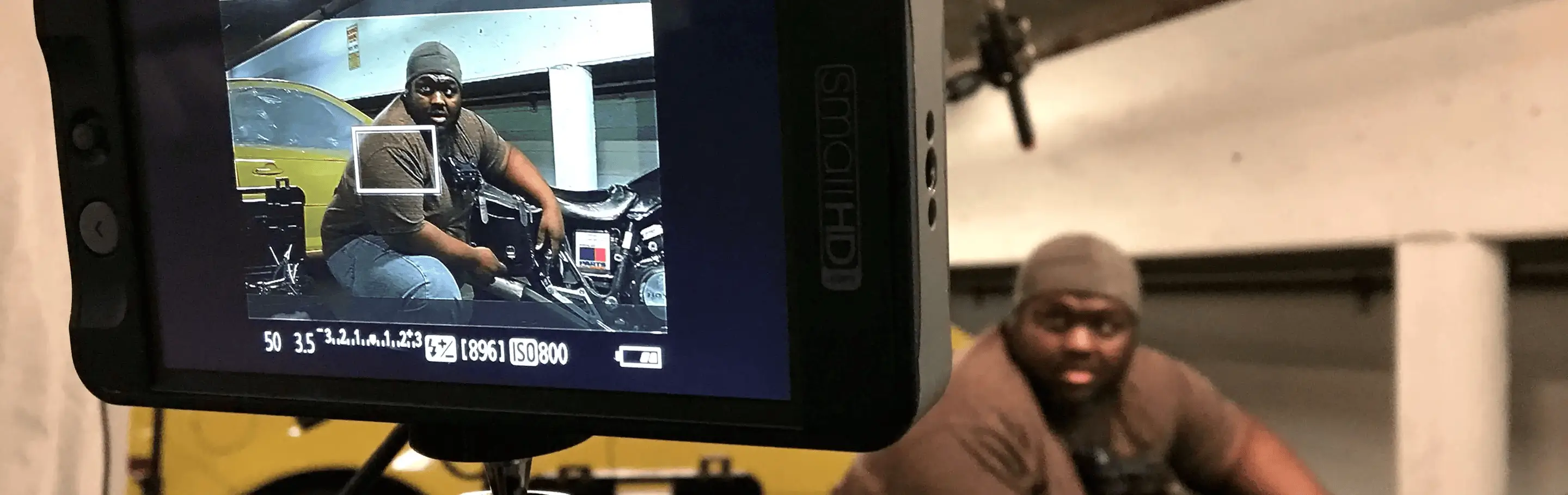 Video monitor mounted on camera showing a guy working on motorcycle