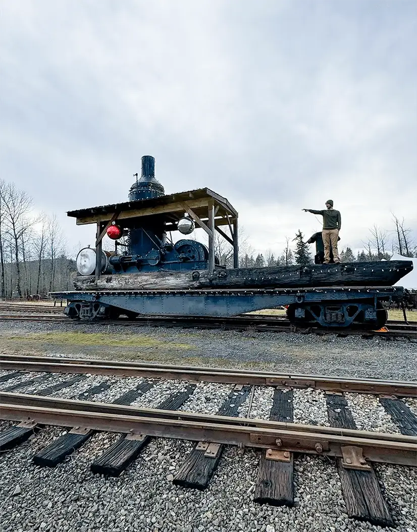 Man Standing on Logging Train poiting in the distance