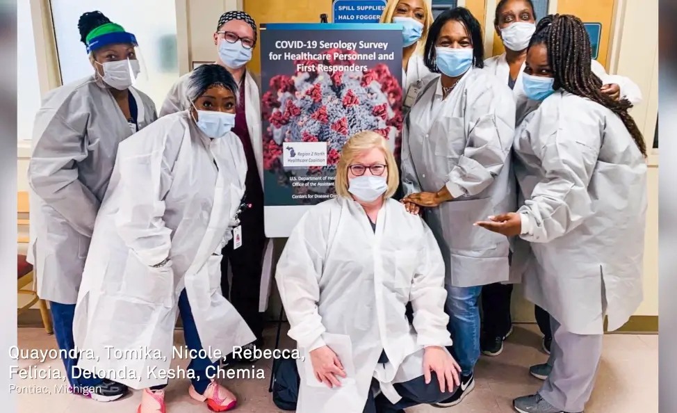 Group of nurses gathered around a Heroes Work Here sign